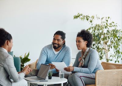 Happy young couple consulting with a UCAN financial educator volunteer to discuss homeownership and financial literacy